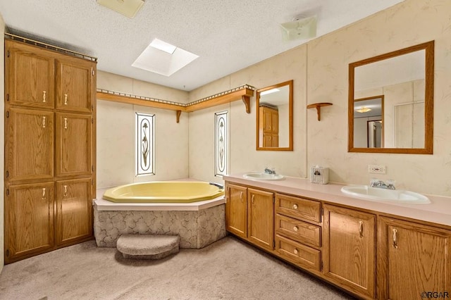 bathroom featuring vanity, a bathtub, a textured ceiling, and a skylight