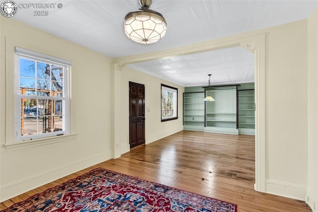 unfurnished dining area with wood-type flooring and built in features