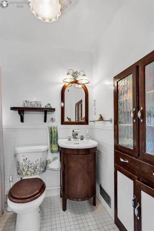 bathroom with french doors, toilet, tile walls, vanity, and tile patterned flooring