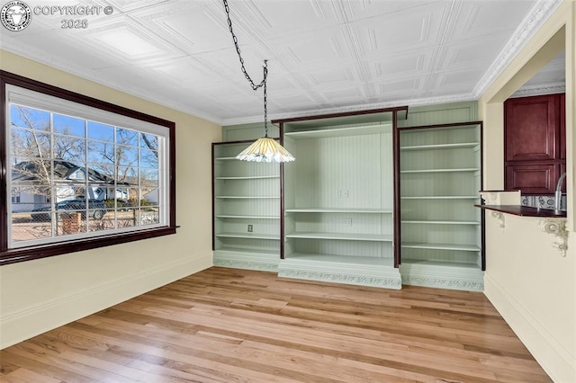 unfurnished dining area featuring light wood-type flooring and built in shelves