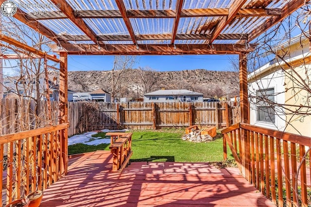 wooden deck with a mountain view, a pergola, and a lawn