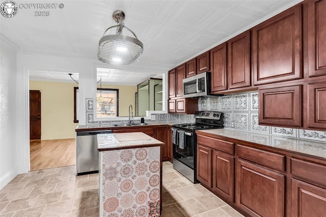 kitchen with sink, appliances with stainless steel finishes, tasteful backsplash, a kitchen island, and decorative light fixtures