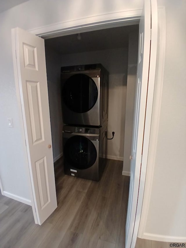 laundry room featuring hardwood / wood-style flooring and stacked washer and clothes dryer