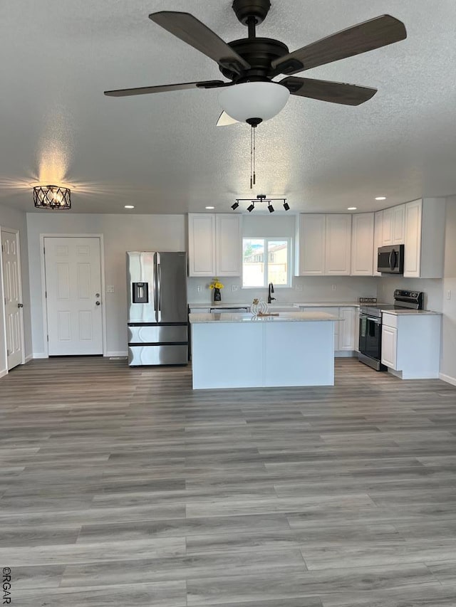 kitchen with appliances with stainless steel finishes, sink, white cabinets, a textured ceiling, and light hardwood / wood-style flooring