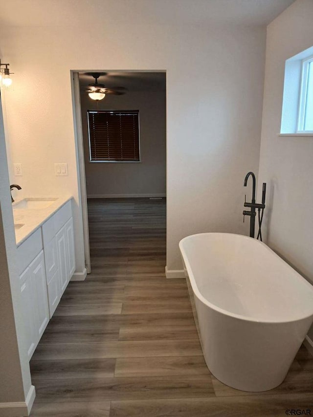 bathroom with hardwood / wood-style flooring, vanity, and a bath