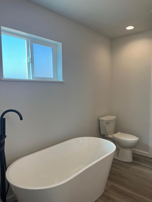 bathroom featuring a bathing tub, wood-type flooring, and toilet