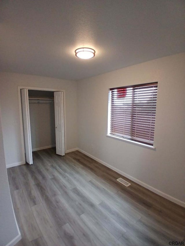 unfurnished bedroom featuring a textured ceiling, a closet, and light wood-type flooring