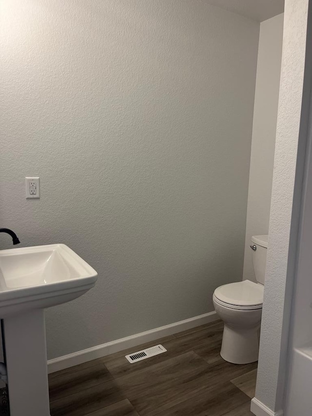 bathroom with hardwood / wood-style flooring, toilet, and sink