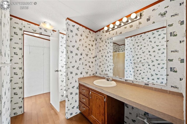 bathroom featuring crown molding, vanity, hardwood / wood-style floors, and a textured ceiling