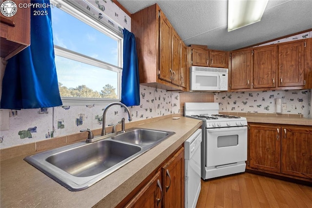 kitchen featuring white appliances, sink, light hardwood / wood-style flooring, and a textured ceiling