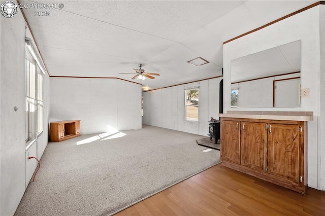 unfurnished living room with ceiling fan, light carpet, and a wood stove