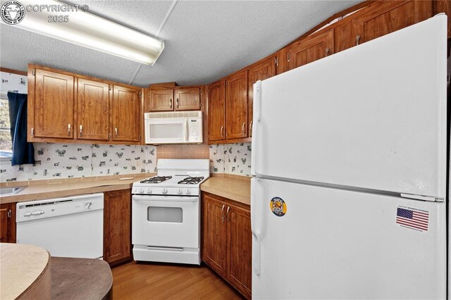 kitchen featuring tasteful backsplash, white appliances, a textured ceiling, and light wood-type flooring