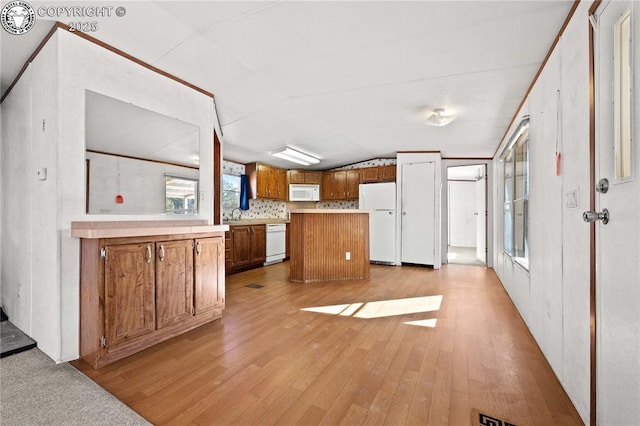 kitchen featuring lofted ceiling, white appliances, light hardwood / wood-style floors, and a center island