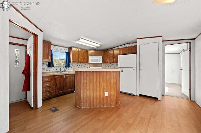 kitchen with white appliances, lofted ceiling, a center island, and light hardwood / wood-style floors