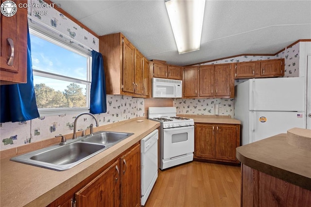 kitchen featuring lofted ceiling, sink, white appliances, light hardwood / wood-style floors, and a textured ceiling