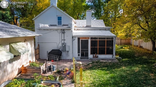 rear view of house featuring a sunroom and a lawn