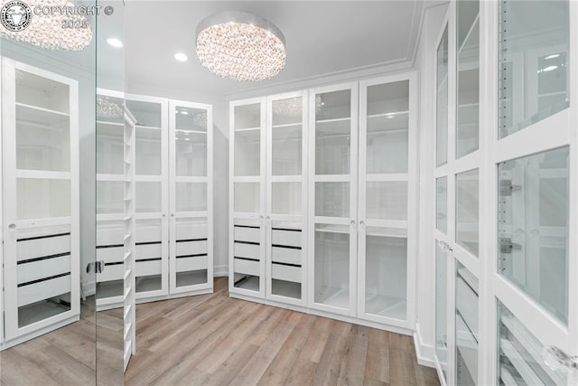 walk in closet featuring light wood-style flooring and a notable chandelier