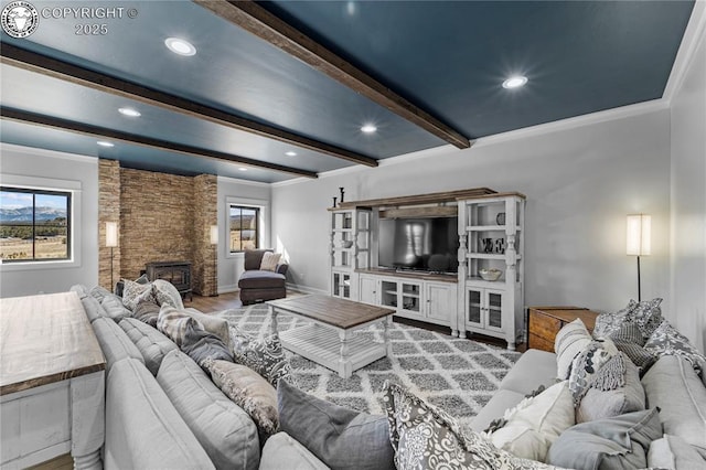 living area with crown molding, recessed lighting, beamed ceiling, and a stone fireplace