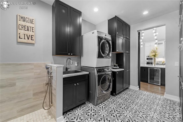 laundry room with wine cooler, stacked washer and dryer, recessed lighting, cabinet space, and a sink