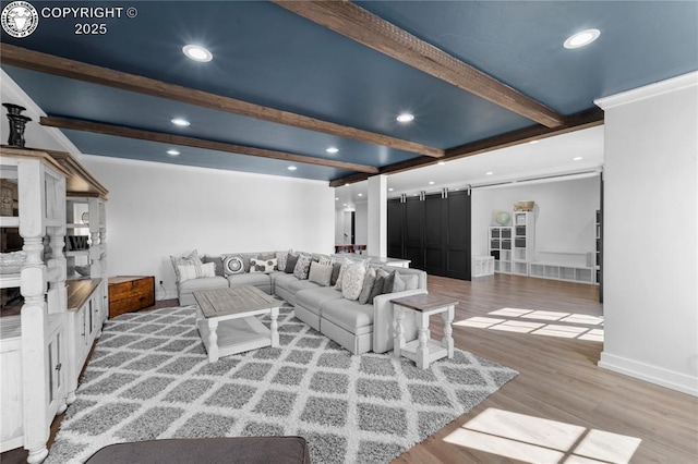 living area with a barn door, baseboards, light wood-style flooring, beam ceiling, and recessed lighting