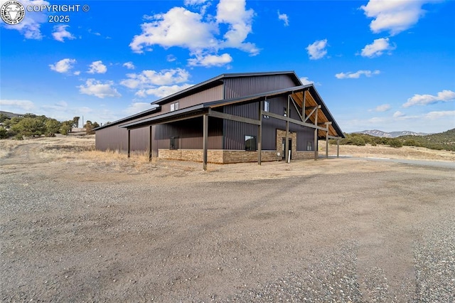 view of home's exterior with a carport, stone siding, and a mountain view