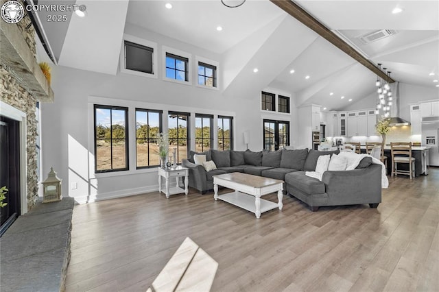 living area featuring baseboards, visible vents, beamed ceiling, light wood-style floors, and high vaulted ceiling