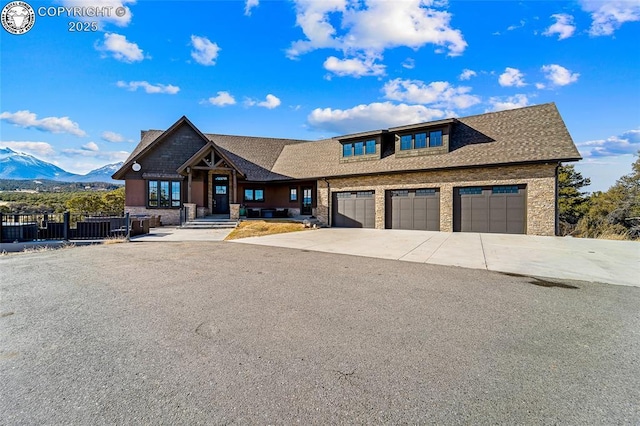 view of front facade featuring an attached garage, a mountain view, a shingled roof, driveway, and stone siding