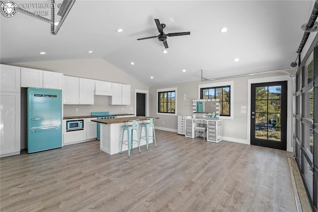 kitchen with stove, light wood-style floors, freestanding refrigerator, white cabinetry, and built in microwave