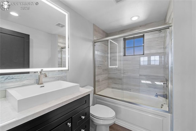 full bathroom featuring visible vents, shower / bath combination with glass door, vanity, and toilet