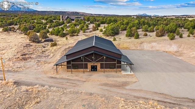 view of front facade with driveway, stone siding, a barn, and an outdoor structure