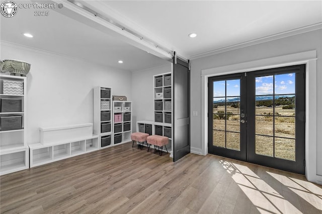 unfurnished room featuring french doors, light wood finished floors, recessed lighting, a barn door, and ornamental molding