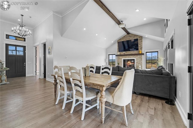 dining area with high vaulted ceiling, a fireplace, baseboards, light wood finished floors, and beamed ceiling