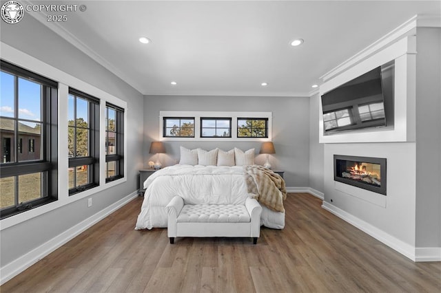 bedroom featuring ornamental molding, wood finished floors, a glass covered fireplace, and baseboards