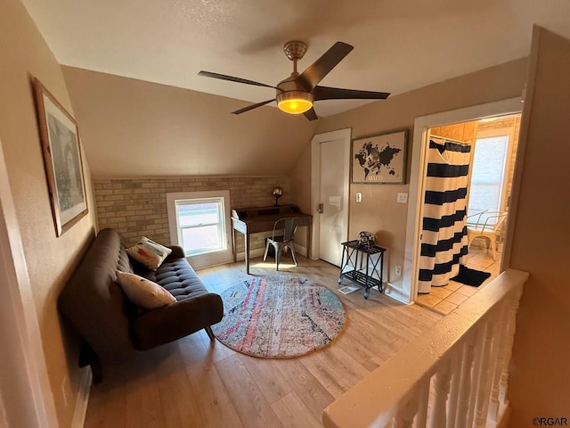 living area featuring ceiling fan, lofted ceiling, brick wall, and wood-type flooring