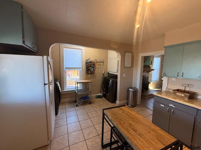 kitchen with light tile patterned flooring, washer and dryer, and white refrigerator