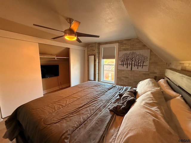 bedroom with brick wall, lofted ceiling, ceiling fan, and a closet