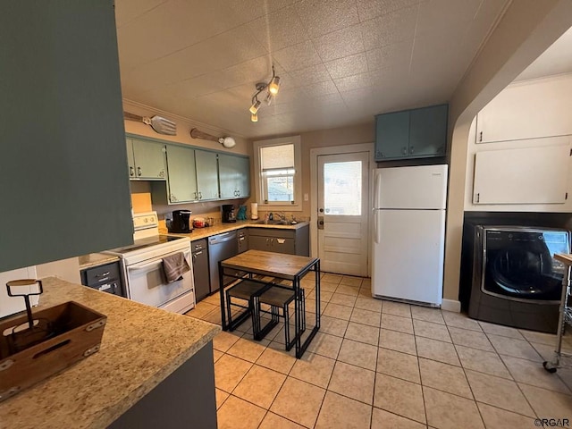 kitchen featuring sink, white appliances, track lighting, light tile patterned flooring, and washer / clothes dryer