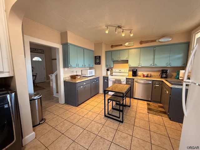 kitchen featuring washer / dryer, light tile patterned floors, and white appliances