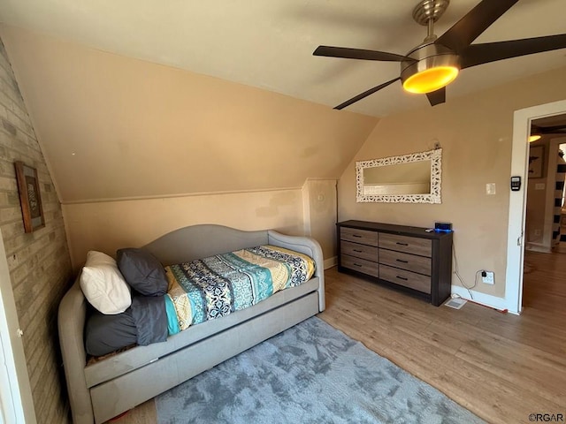 bedroom with ceiling fan, vaulted ceiling, and hardwood / wood-style floors