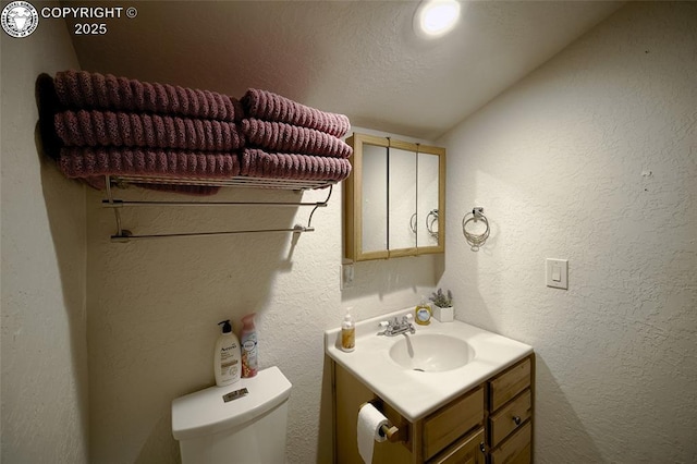 bathroom with vanity, toilet, and a textured ceiling