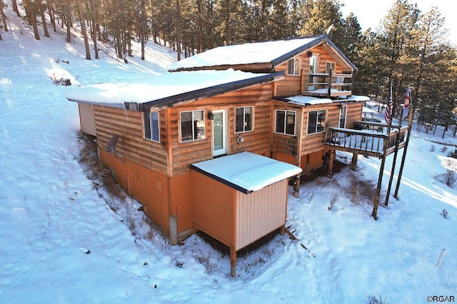 snow covered back of property with a deck