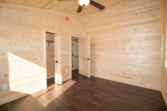 spare room with wood ceiling, vaulted ceiling, wooden walls, dark hardwood / wood-style flooring, and ceiling fan