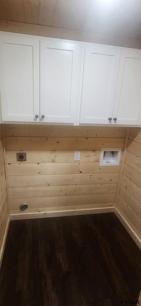 laundry area with cabinets, dark wood-type flooring, hookup for an electric dryer, and wooden walls