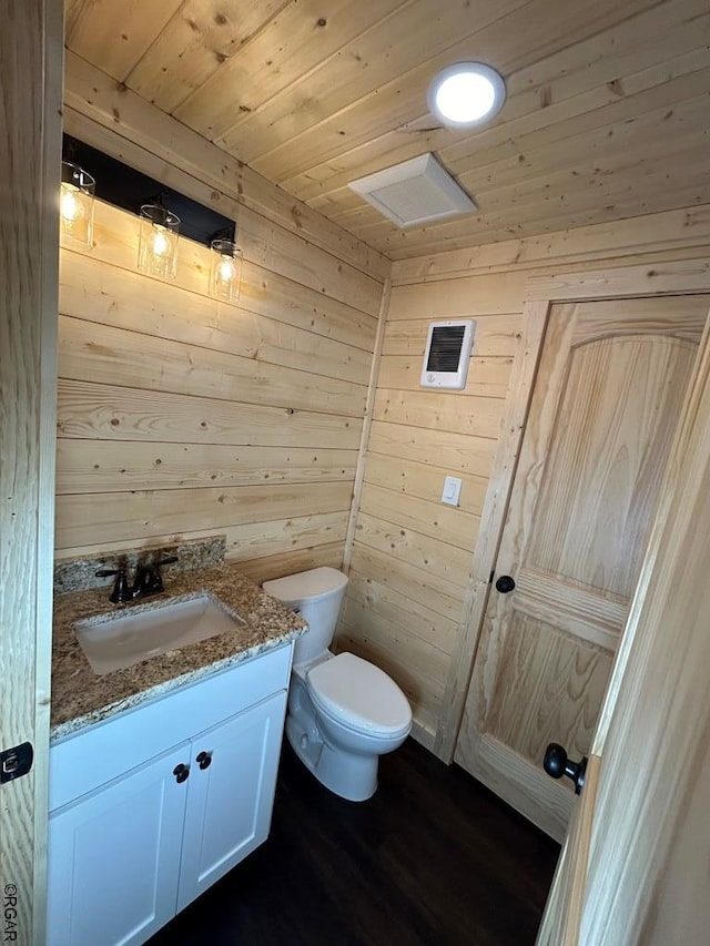 bathroom with wooden walls, hardwood / wood-style flooring, vanity, wood ceiling, and toilet