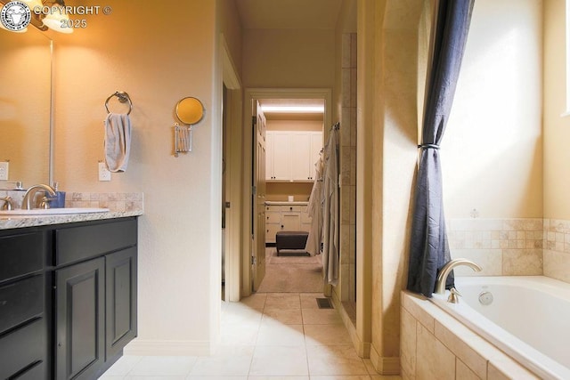 full bathroom featuring tile patterned flooring, vanity, baseboards, a bath, and a walk in closet