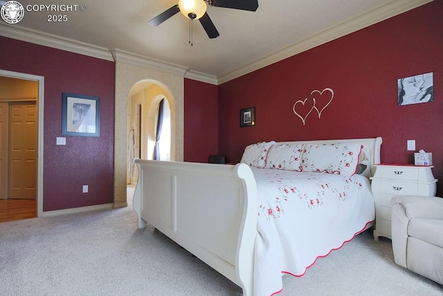 bedroom with arched walkways, crown molding, light carpet, ceiling fan, and baseboards