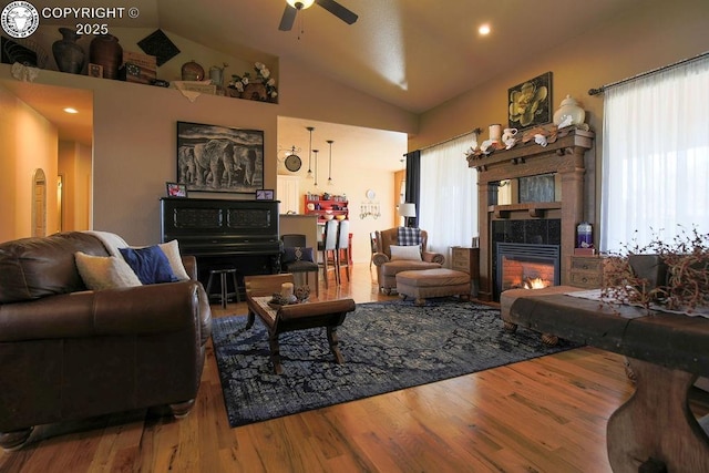 living area with recessed lighting, a tiled fireplace, a ceiling fan, vaulted ceiling, and wood finished floors