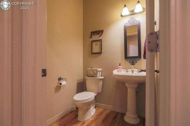 bathroom with baseboards, toilet, and wood finished floors