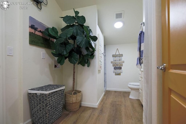 bathroom with toilet, baseboards, visible vents, and wood finished floors