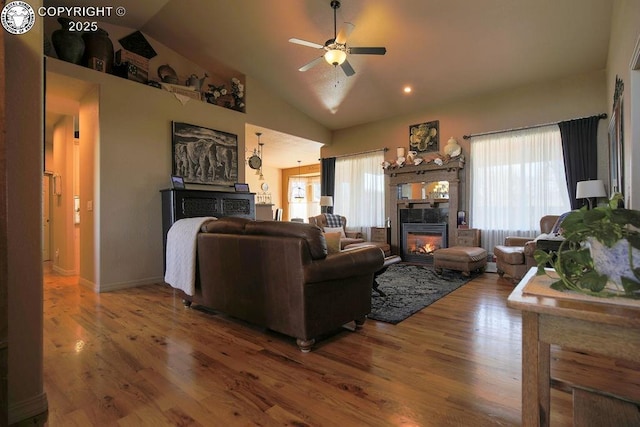 living room with a ceiling fan, a glass covered fireplace, lofted ceiling, and wood finished floors